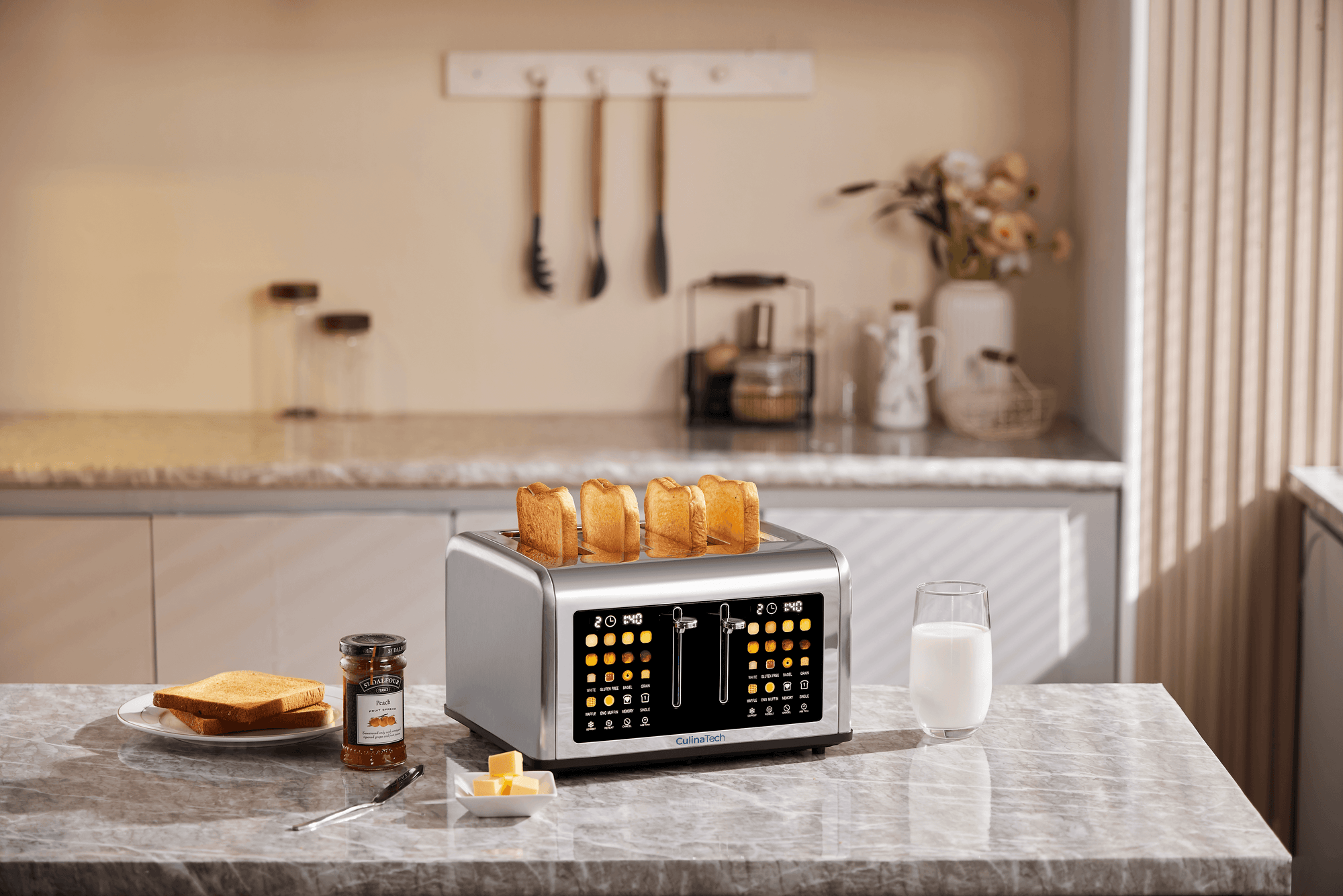 A toaster with four slices of toasted bread sits on a kitchen counter alongside a glass of milk, butter, and jam, with kitchen utensils hanging in the background.